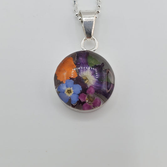 Small round resin pendant with real multi colored flowers.