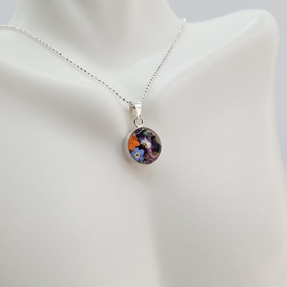 Small round resin pendant with real multi colored flowers.